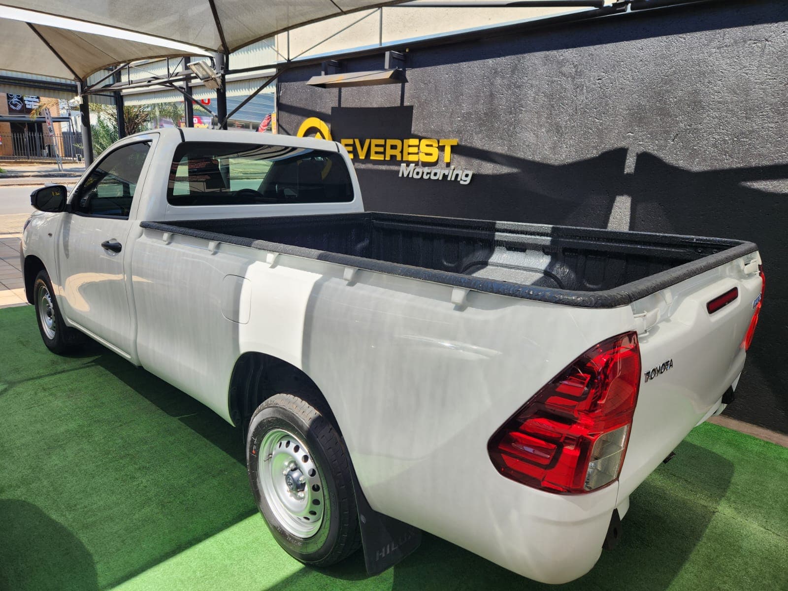 Rear three-quarter exterior view of the white 2025 Toyota Hilux 2.4 GD Single-Cab, showing tailgate and taillight.